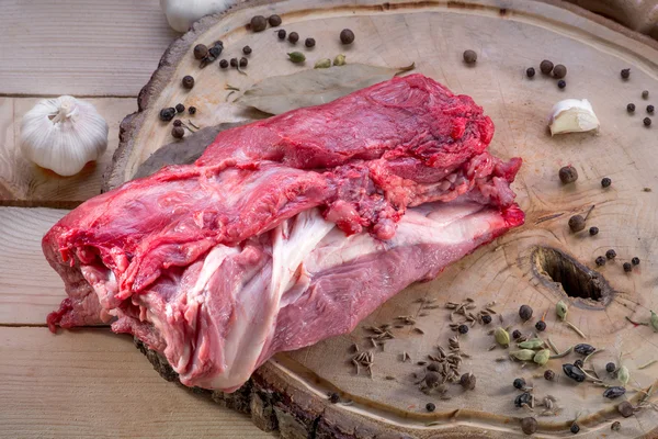 Um grande pedaço de carne crua na mesa de madeira com especiarias — Fotografia de Stock