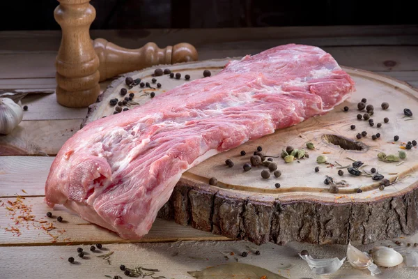 A big piece of raw meat on wooden desk with spices — Stock Photo, Image