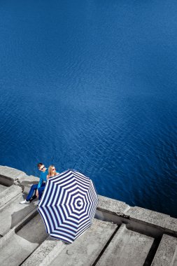 iskelede plaj şemsiyesi ile su b üzerinde oturan Çift