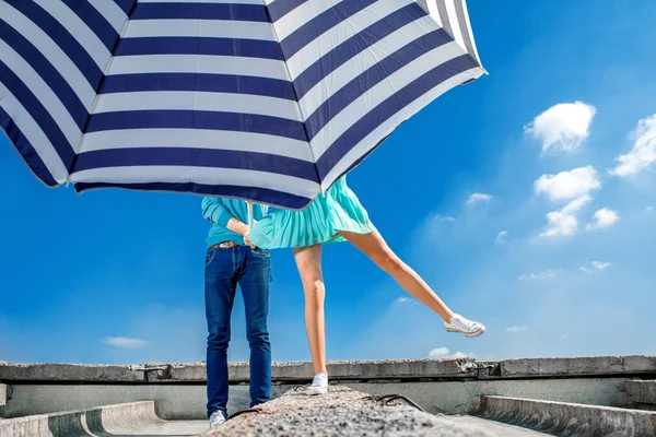 Пара, прячущаяся под пляжным зонтиком на крыше голубого неба b — стоковое фото