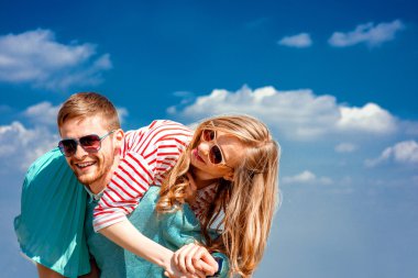 mutlu çift kucaklayan ve mavi gökyüzü altında eğleniyor