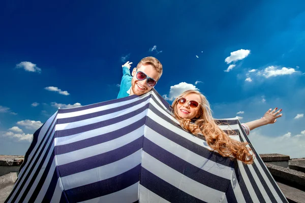 Emotional couple flying with umbrella and having fun on the blue — Stock Photo, Image