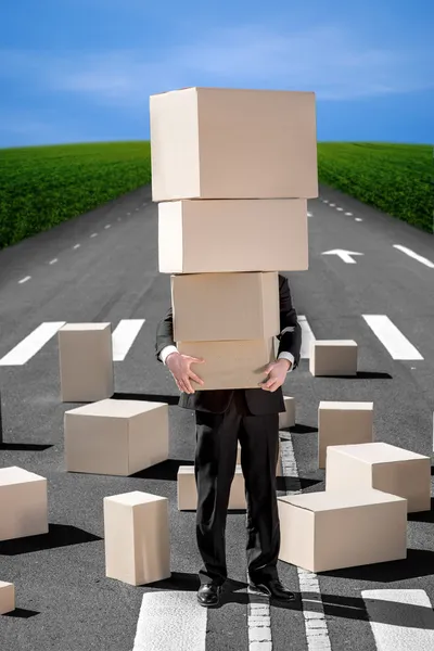 Business man holding carton boxes on the road with a lot of boxe — Stock Photo, Image