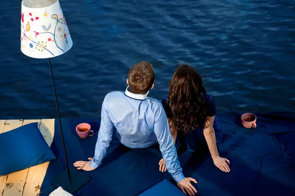 Jovem casal apaixonado relaxante no terraço perto da água — Fotografia de Stock