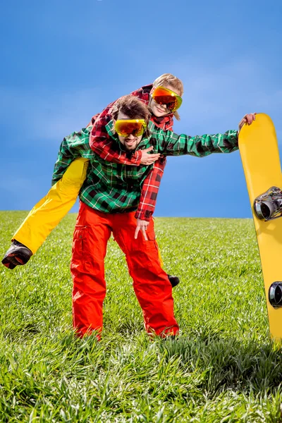 Homem de ternos de esqui dando passeio de piggyback para namorada com snowbo — Fotografia de Stock