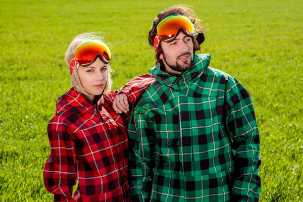 Couple in ski suits and sun glasses standing side by side with s — Stock Photo, Image