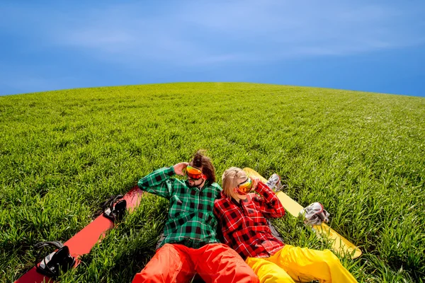 Couple in sportswear with snowboards lying on the grass — Stock Photo, Image