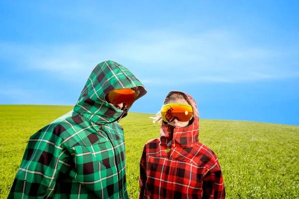 Couple in the ski suits standing in the green field — Stock Photo, Image