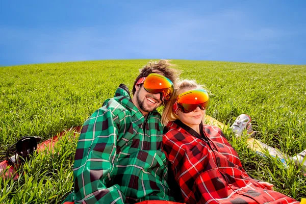 夫妇在运动服与滑雪板躺在草地上 — 图库照片