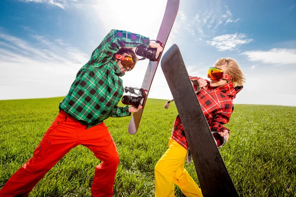 Jeune couple en combinaison de ski ont bataille amusante avec snowboards ensemblele — Photo