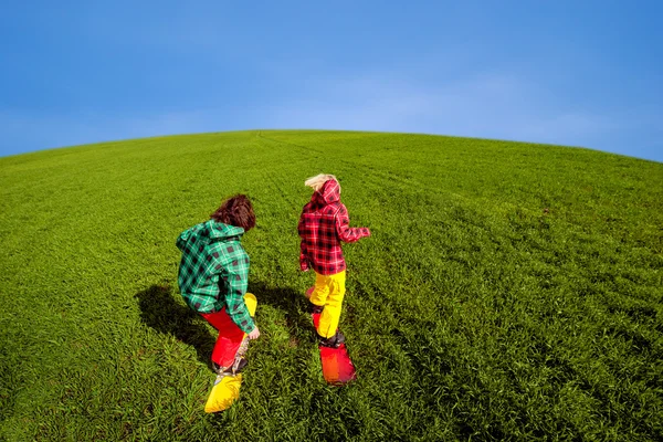 年轻的夫妇在运动服滑雪在绿色的草地上 — 图库照片