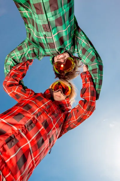 Couple en combinaison de ski avec des lunettes de soleil tenant la main sur le ciel bleu ba — Photo