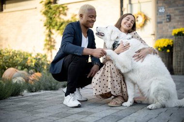 Çok ırklı çiftler evlerinin yakınında köpekleri okşarlar.