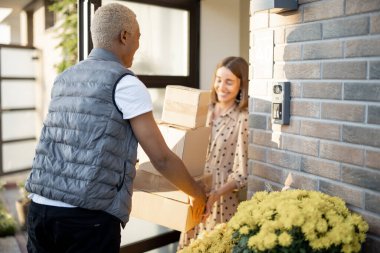 Teslimatçı, beyaz bir kadına paket veriyor.