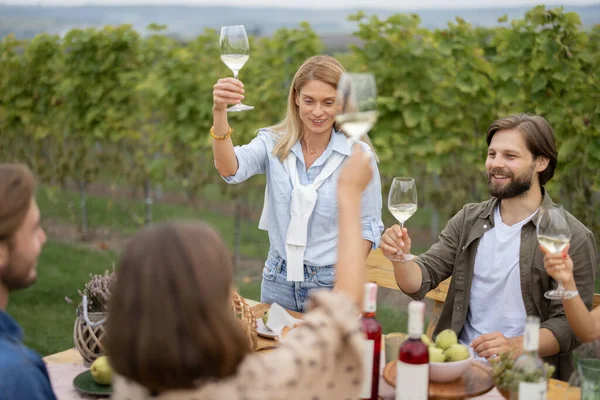 Vrienden die wijn drinken bij de picknick bij wijngaarden — Stockfoto