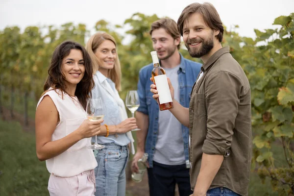 Barátok kóstoló bor közelében szőlőültetvények vidéken — Stock Fotó