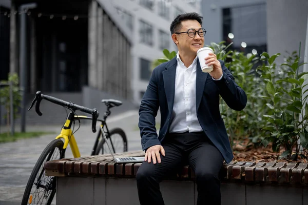 Asiatisk affärsman dricker kaffe på stadens gata — Stockfoto