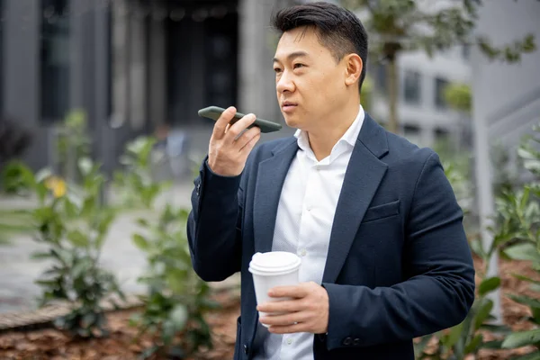 Empresário com xícara de café chamando no smartphone — Fotografia de Stock