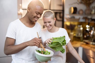 Ev mutfağında salata yiyen çok ırklı bir çift.