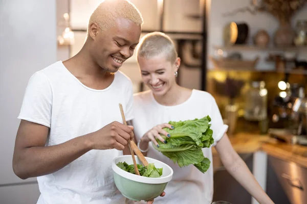 Ev mutfağında salata yiyen çok ırklı bir çift.