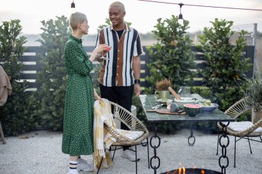 Çok ırklı bir çift akşamları arka bahçelerinde yemek yerken birlikte takılıyor. Bardakları tokuşturuyorum. İlişki kavramı. Siyahi adam ve Avrupalı kadın birlikte vakit geçiriyorlar.