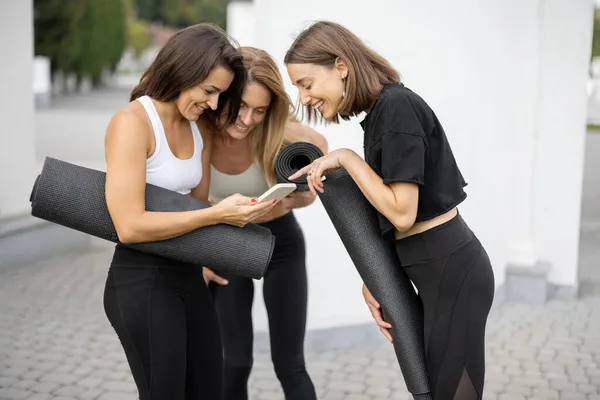 Chicas de pie con colchonetas de fitness y hablar al aire libre — Foto de Stock