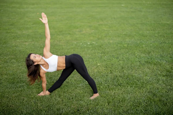 Chica joven practicando yoga en el prado verde — Foto de Stock
