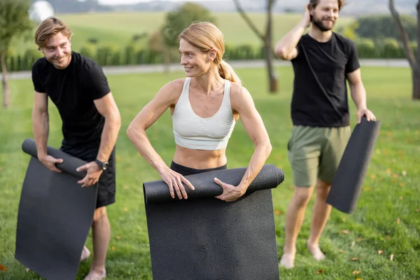Mensen vouwen fitnessmatten na het trainen op de weide — Stockfoto