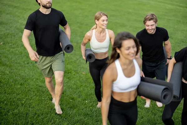 Oamenii care merg cu covoare de fitness pe pajiște verde — Fotografie, imagine de stoc