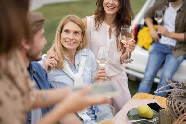 Vänner som dricker vin på picknick nära vingårdar — Stockfoto