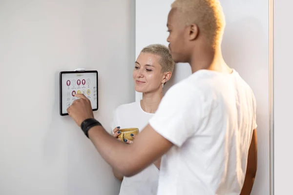 Νεαρό ζευγάρι που ελέγχει έξυπνες οικιακές συσκευές σε ένα ψηφιακό tablet — Φωτογραφία Αρχείου