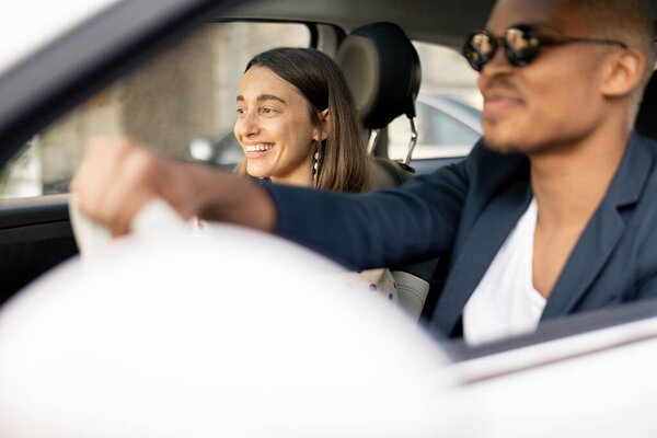 Happy multiracial couple driving at car together