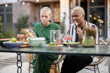 Çok ırklı bir çift arka bahçelerinde yemek yiyor.
