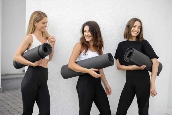 Dívky stojí s fitness rohožemi a mluvit venku — Stock fotografie