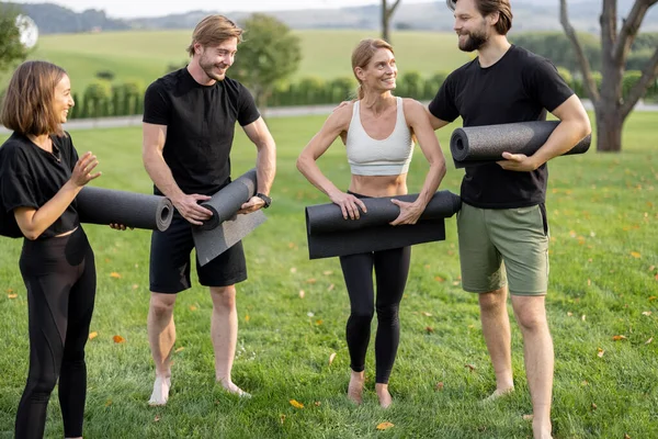 İnsanlar çayırda çalıştıktan sonra spor paspaslarını katlıyorlar. — Stok fotoğraf