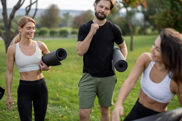 Ludzie z matami fitness stoją na zielonej łące — Zdjęcie stockowe