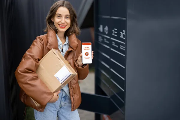 Дівчина з посилкою і телефоном з смарт-додатком доставки — стокове фото