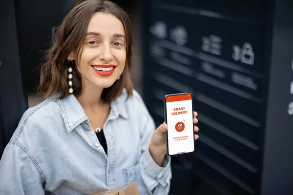 Chica con paquete y teléfono con aplicación de entrega inteligente — Foto de Stock