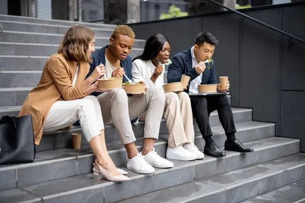 Geschäftsteam spricht, isst und trinkt auf der Treppe — Stockfoto