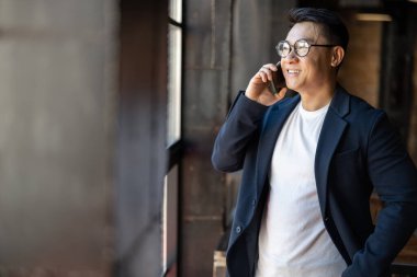 Adam akıllı telefondan konuşur ve pencereden bakar.