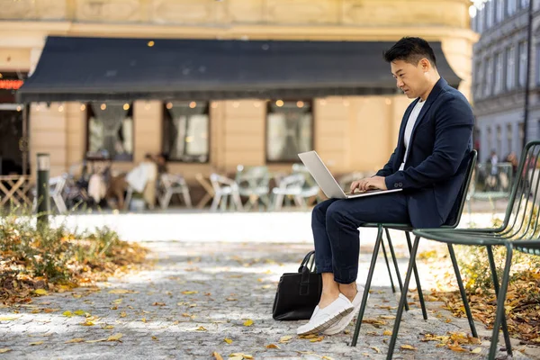 Businessman typing on laptop during work outdoors — Stock Photo, Image