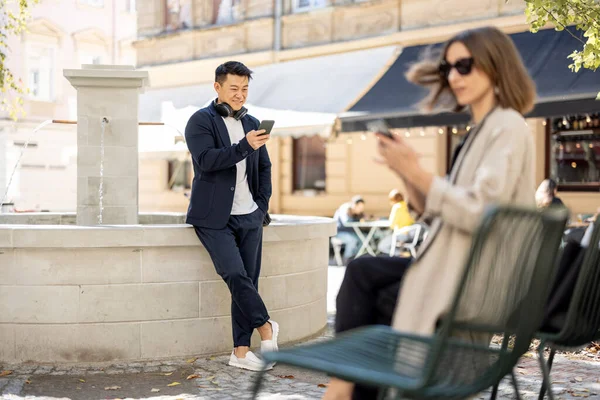 Mujer y hombre usando teléfonos inteligentes en el área de la ciudad — Foto de Stock