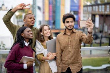 Genç öğrenciler açık havada akıllı telefondan selfie çekiyorlar.