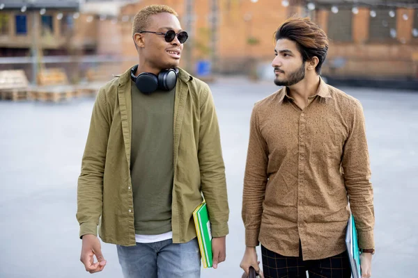 Estudantes do sexo masculino andam e conversam no campus universitário — Fotografia de Stock