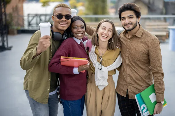 若い学生抱擁し、屋外カメラを見て — ストック写真