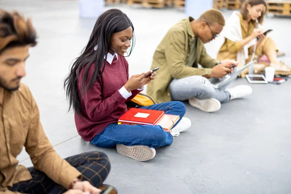Az aszfalton ülő és okostelefonokat használó diákok — Stock Fotó