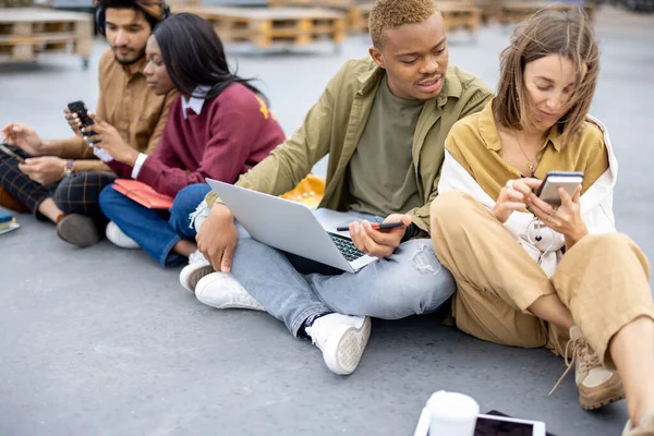 Studenten sitzen und bedienen Geräte auf Asphalt — Stockfoto