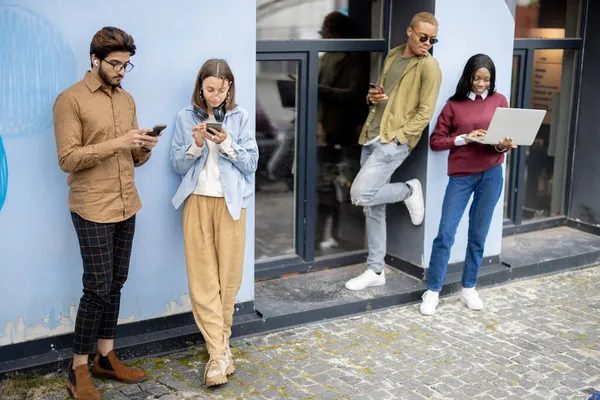 Mladí studenti používají gadgets na univerzitě budovy — Stock fotografie