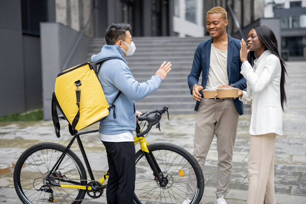 Courier giving food order to business people