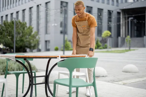 Офіціант виправляє стілець за столом у відкритому кафе — стокове фото